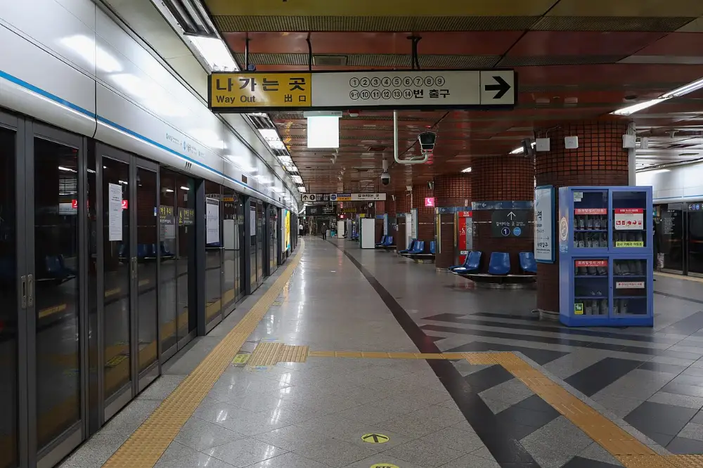 An empty platform at Seoul Station on subway Line 4 with screen doors and exit signs
